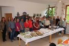 Zahlreiche Frauen und ein Mann stehen in einer breiten Reihe hinter einem Speisenbuffet.