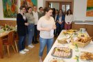 Gruppe von Personen steht vor Buffet mit Speisen.