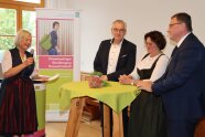 Runder Stehtisch mit grüner Decke, links Frau mit Mikrofon, rechts zwei Männer und eine Frau.