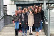 Gruppenbild von mehreren Personen auf einer Treppe vor einem Gebäudeeingang.