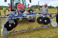 Mann begutachtet Mähwerk an Traktor.