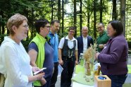 Mehrere Personen hören aufmerksam einer Frau zu, die über Landwirtschaft informiert und Ähren vorzeigt.