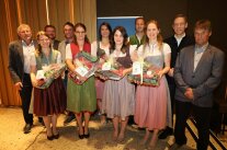 Elf Personen, davon viele in Tracht, in der vorderen Reihe Frauen mit Präsenten in den Händen.
